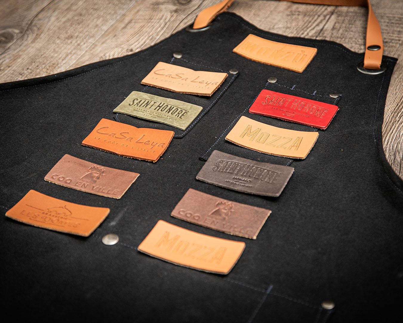 Leather jacrons embossed with client restaurant logos on a black apron